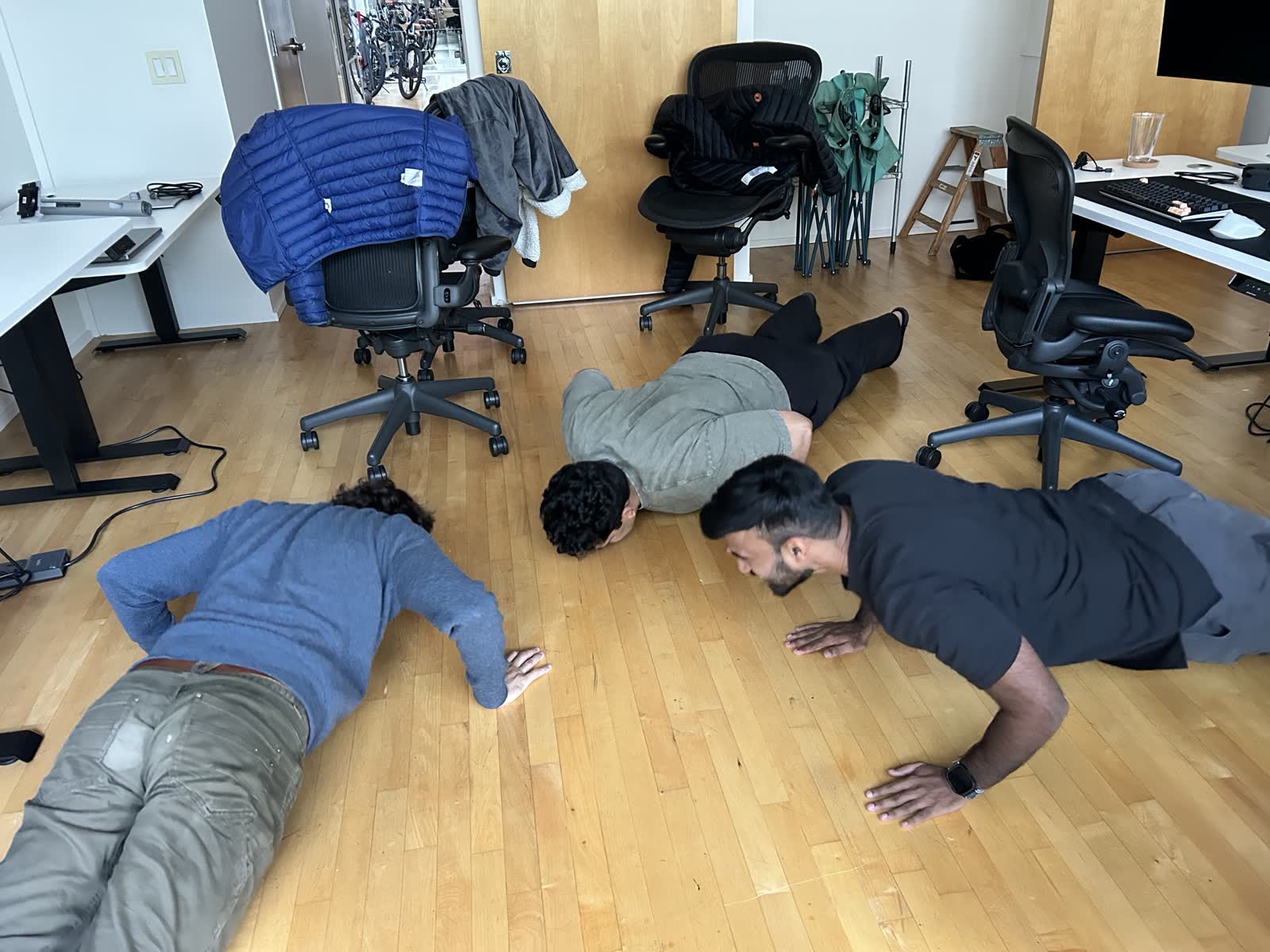 Avi, Satya, and Harshith do pushups on the office floor